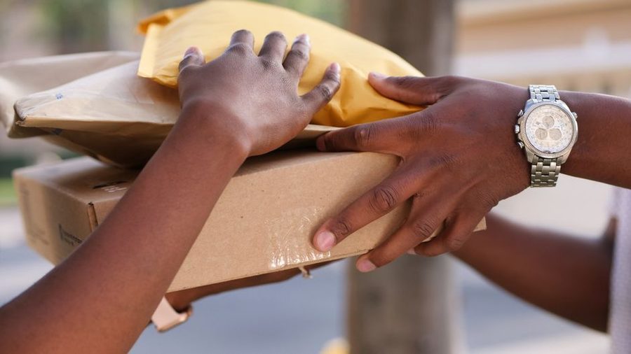 Caixas de papelão empilhadas ao lado de um notebook aberto mostrando um carrinho de compras online, representando o cálculo do frete em uma compra